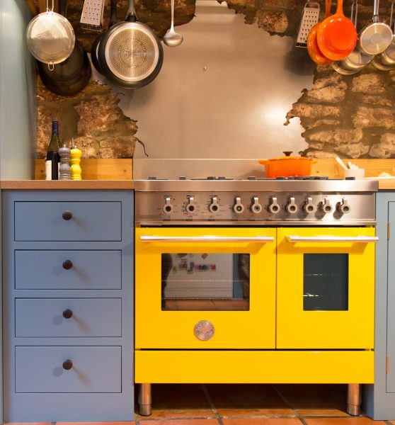 Blue shaker style kitchen with bright yellow cooker